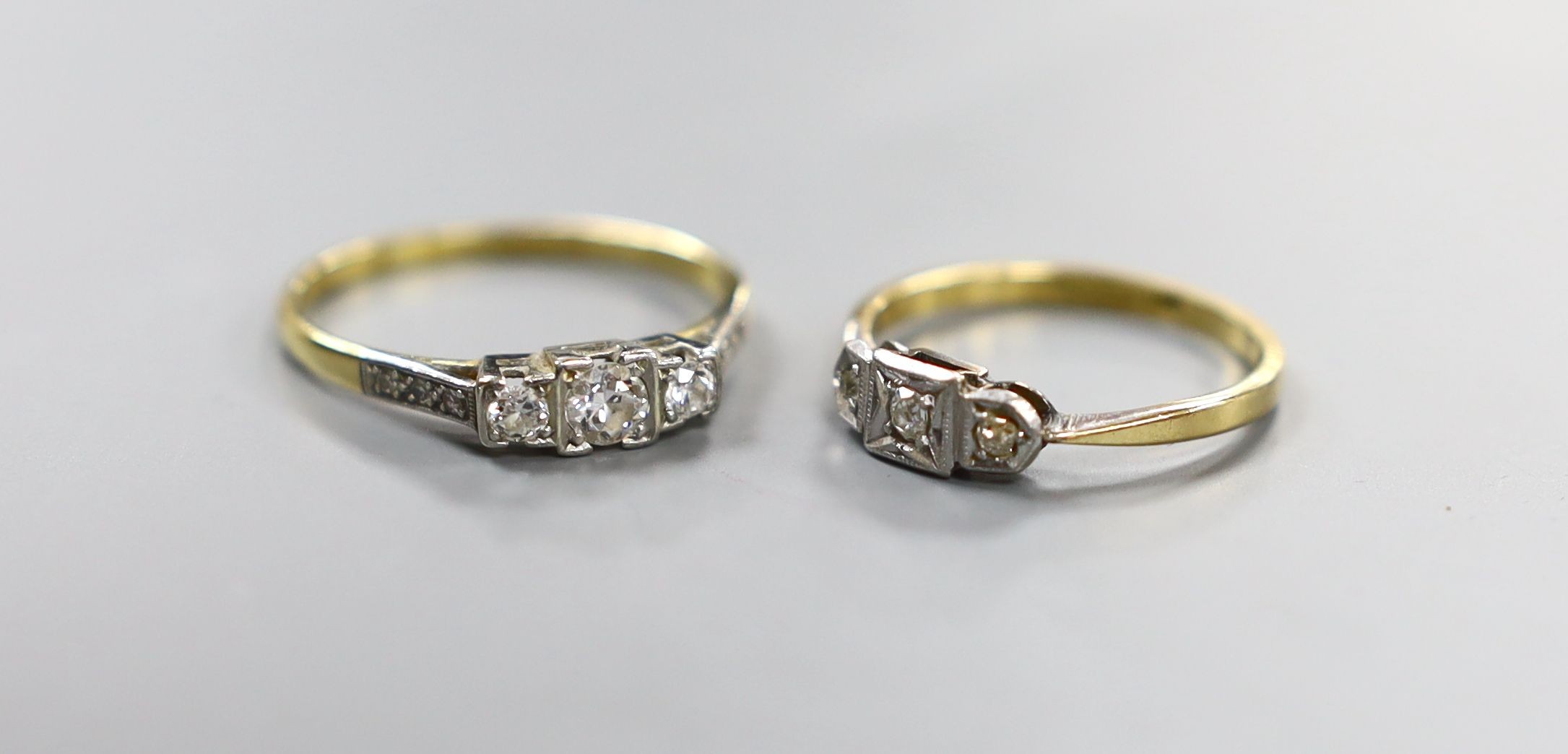 Two early 20th century yellow metal (one stamped 18ct & plat) and three stone diamond rings, one with diamond set shoulders, sizes N & Q, gross weight 4.1 grams.